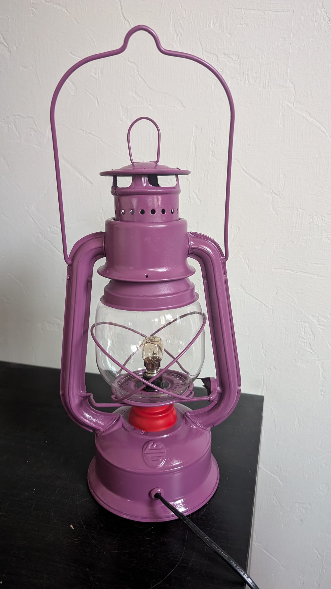 Profil de la lampe industrielle restaurée montrant sa robe violette et sa poignée