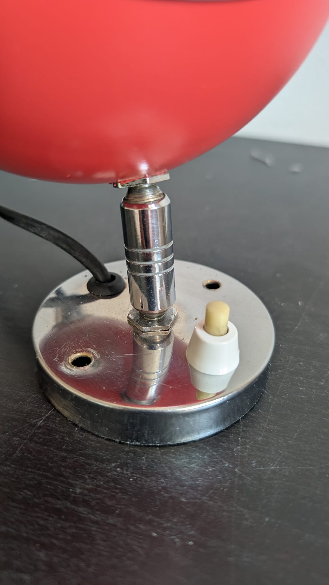 Gros plan sur la rotule directionnelle en chrome et l'interrupteur blanc du socle d'applique