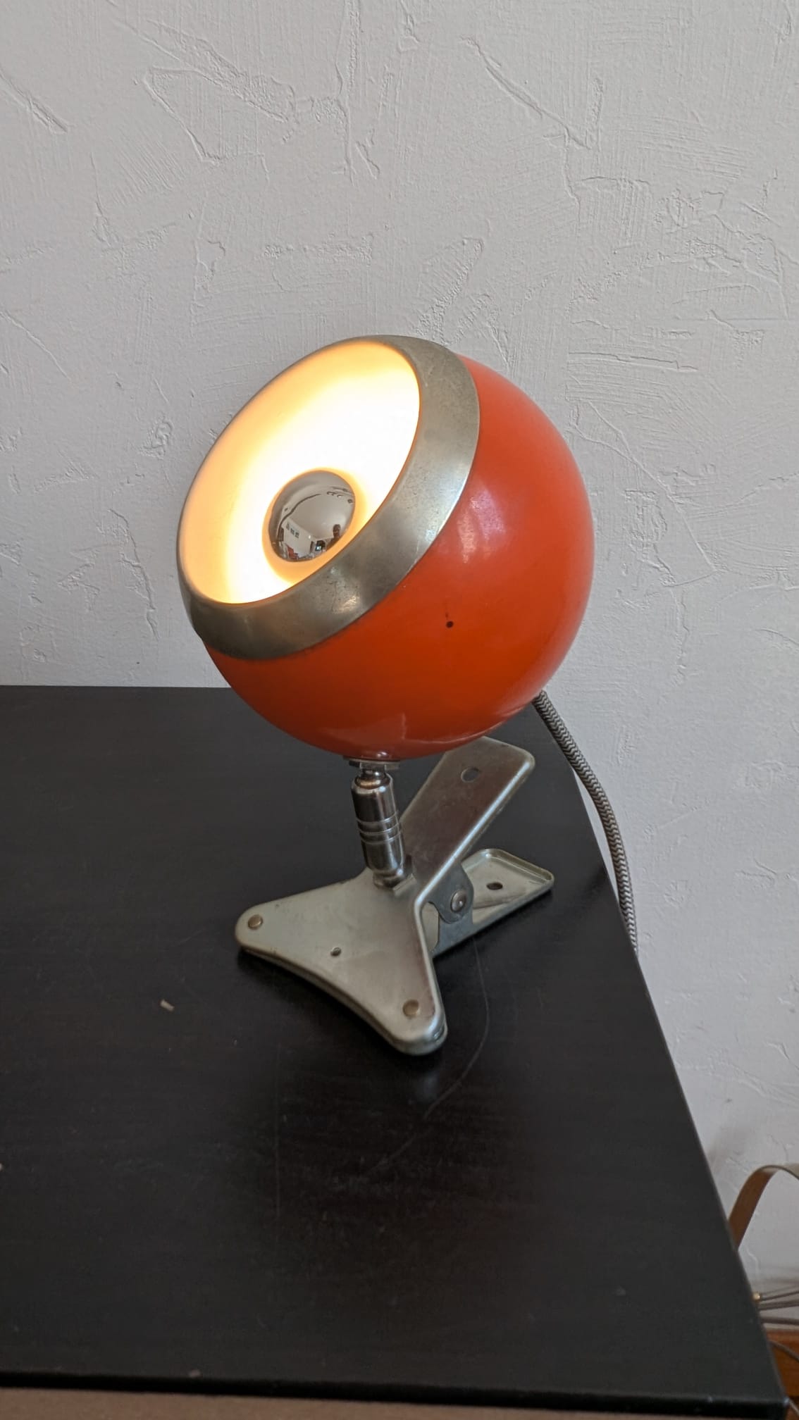 Vue de trois-quarts d'une lampe Eyeball orange Space Age allumée